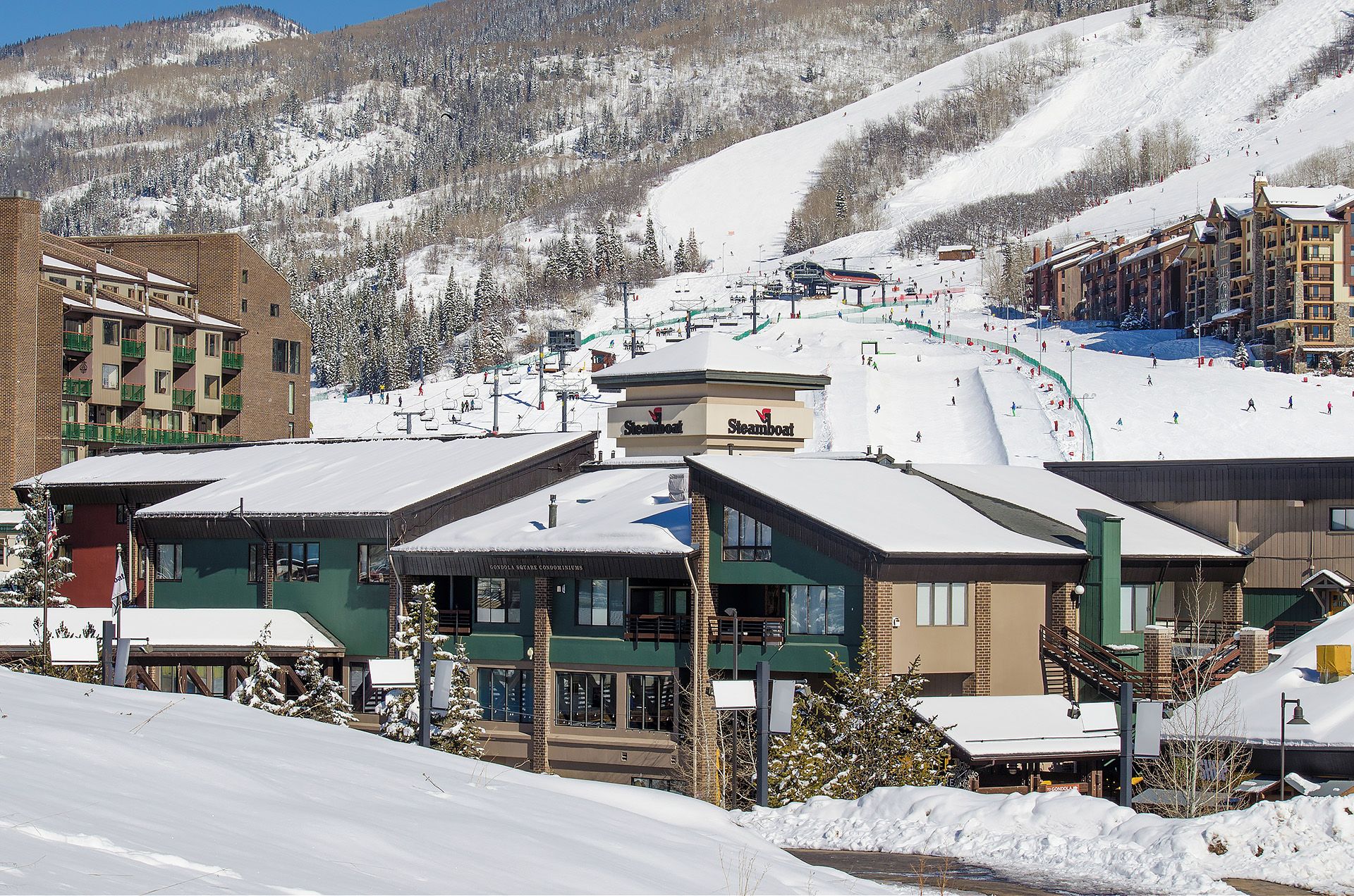 Un centro de esquí con edificios, un telesilla y pistas cubiertas de nieve.