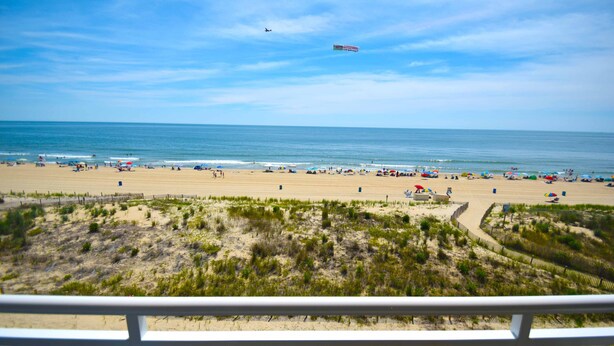 Una playa con cielo despejado, orilla de arena y algunas sombrillas.