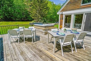 An outdoor deck with a hot tub, dining table, and chairs. - Sunburst home sleeps 16 with an indoor and outdoor hot tub.  Perfect for family reunions and getaways. (Killington)