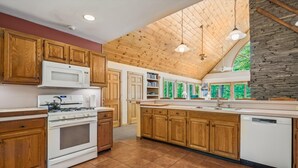 A kitchen with wooden cabinets, a stove, a microwave, and a dishwasher. - Sunburst home sleeps 16 with an indoor and outdoor hot tub.  Perfect for family reunions and getaways. (Killington)