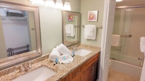 A bathroom with two sinks, a large mirror, and a shower.