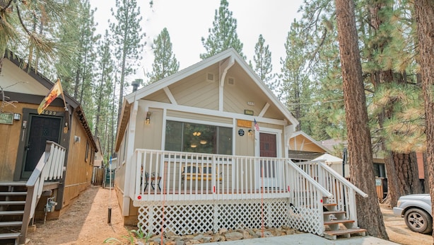 A cabin with a porch, wooden exterior, and a small staircase leading to the entrance. - Moonridge Mountain - Hot Tub, Fenced Yard, BBQ, Walk to shops (Big Bear Lake)