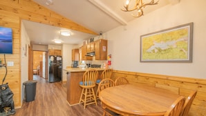 A wooden interior with a dining area, kitchen, and a map on the wall. - Moonridge Mountain - Hot Tub, Fenced Yard, BBQ, Walk to shops (Big Bear Lake)