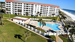 Un hotel con piscina, vista sulla spiaggia e diversi balconi.