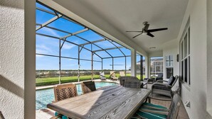 Un patio couvert avec une piscine, du mobilier d’extérieur et un ventilateur de plafond.