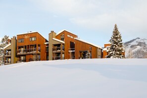 A multi-story hotel with balconies and a snowy landscape in the background.