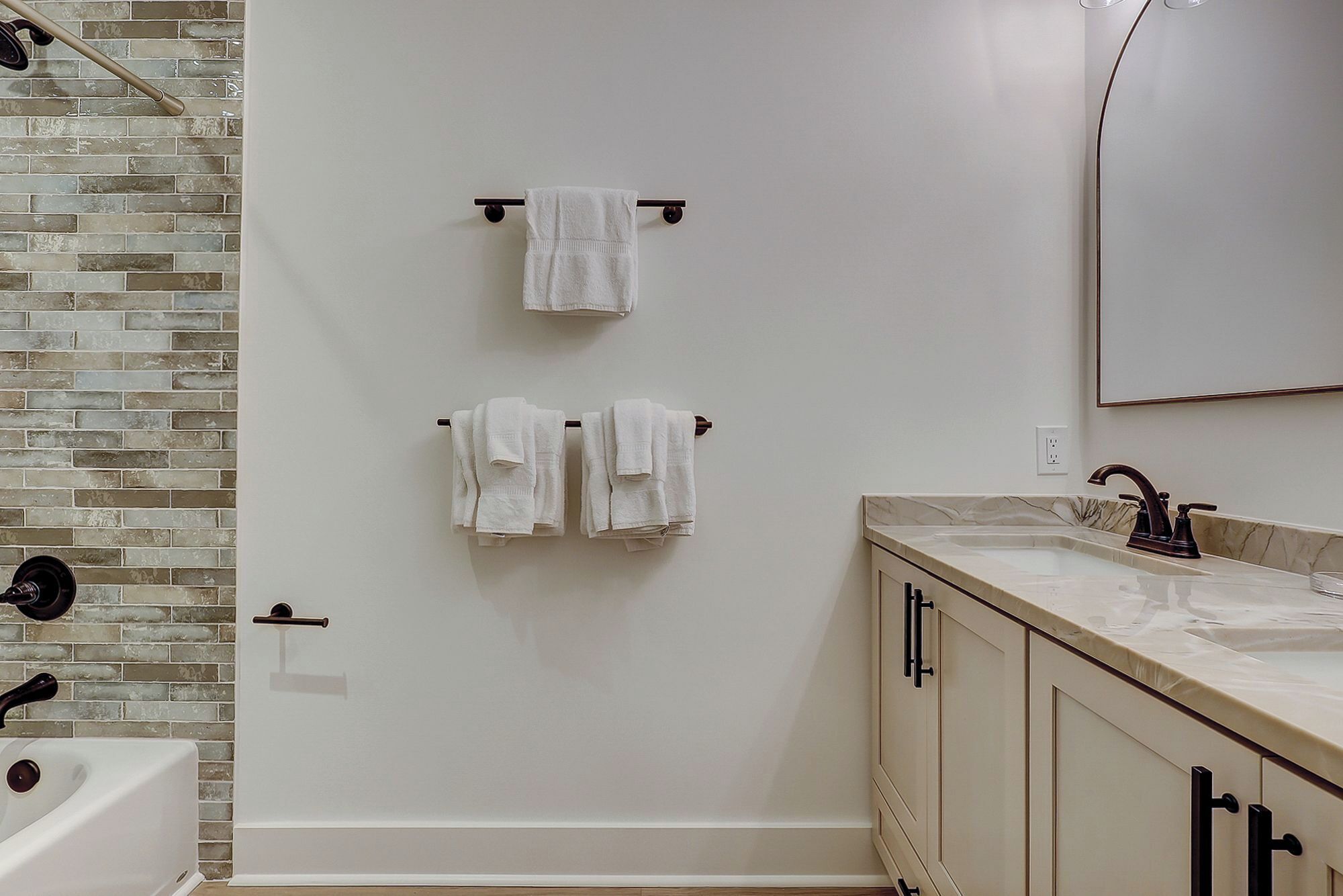 Un baño con una bañera blanca, un lavabo con encimera de mármol y un espejo sobre el lavabo.