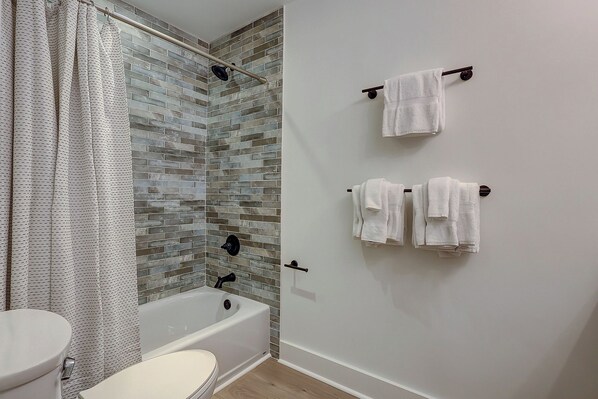 A bathroom with a bathtub, shower curtain, and tiled walls. - Oceanfront Villa, Heated Beachside Pool! (Hilton Head)