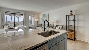 A modern kitchen with a large island, a built-in sink, and a view of the outdoors. - Oceanfront Villa, Heated Beachside Pool! (Hilton Head)