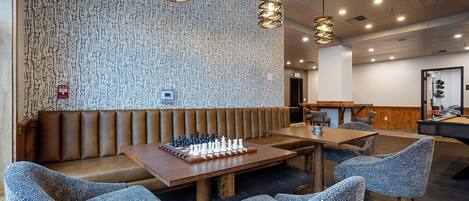 A modern dining area with a wooden table, chess set, and patterned chairs.