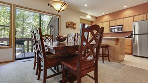 A modern kitchen with wooden cabinets, stainless steel appliances, and a dining area with a wooden table and chairs. - The Ridge at Sunriver - Condo #42 - Access provided to onsite seasonal swimming pool & tennis facilities, year-round hot tub plus 4 bikes (Sunriver)