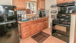 Una cocina con gabinetes de madera, un refrigerador de acero inoxidable, un microondas, una estufa y un lavaplatos.