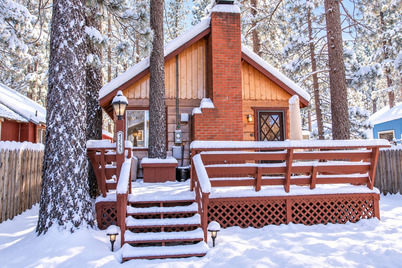 A wooden cabin with a brick chimney, surrounded by snow-covered trees.