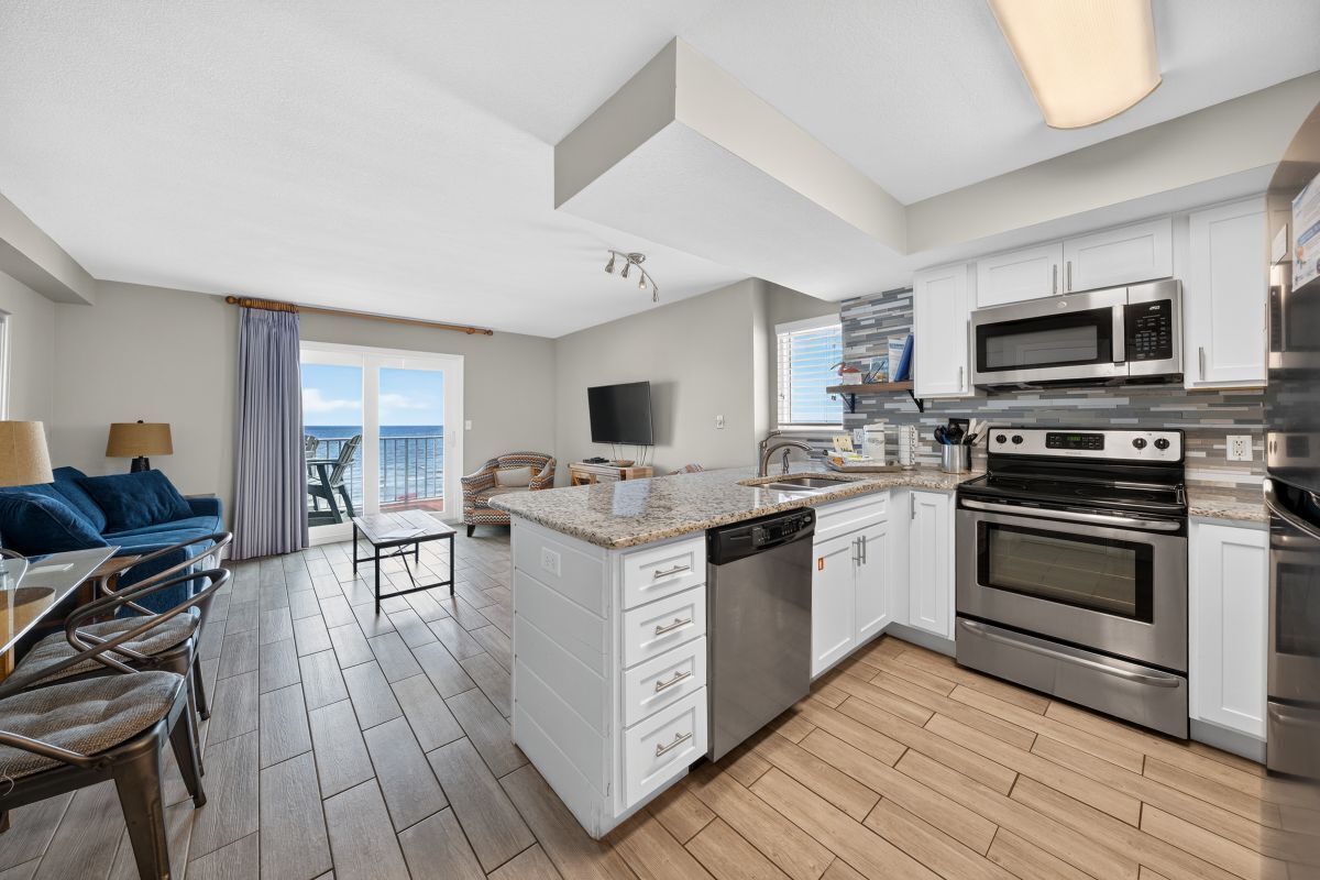 A modern kitchen with white cabinets, stainless steel appliances, and a large island with a dishwasher.