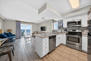 A modern kitchen with white cabinets, stainless steel appliances, and a large island with a dishwasher.