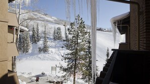 A snowy landscape with icicles hanging from a building's roof, a snow-covered slope, and evergreen trees. - SE064 | Great Ski Access | Winter Shuttle | Hot Tub (Steamboat Springs)