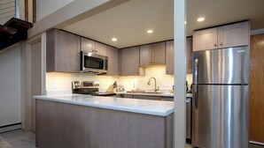 A modern kitchen with stainless steel appliances, a central island, and wooden cabinets. - SE064 | Great Ski Access | Winter Shuttle | Hot Tub (Steamboat Springs)