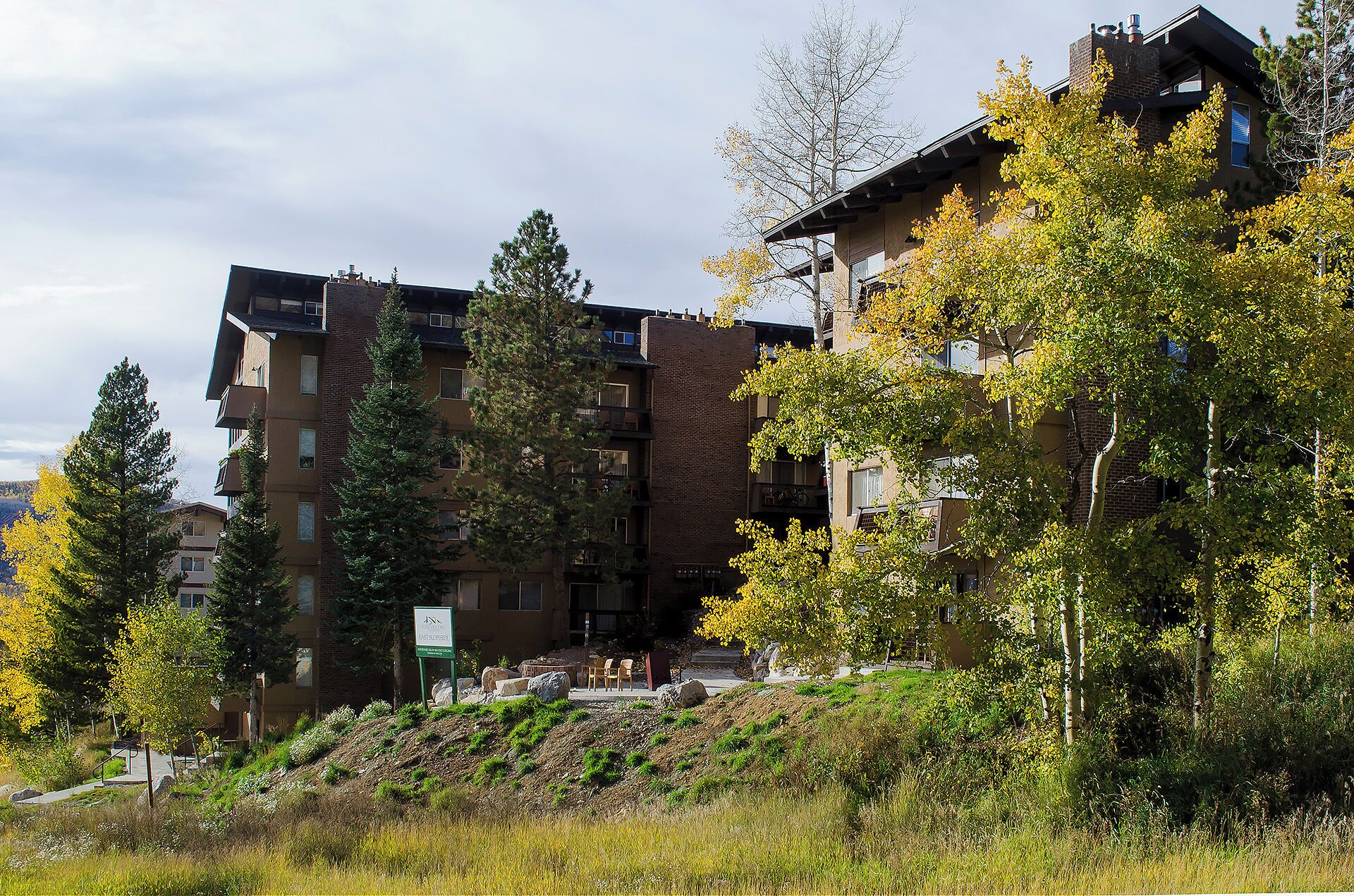 A multi-story building with a brick facade, surrounded by trees and a grassy area.