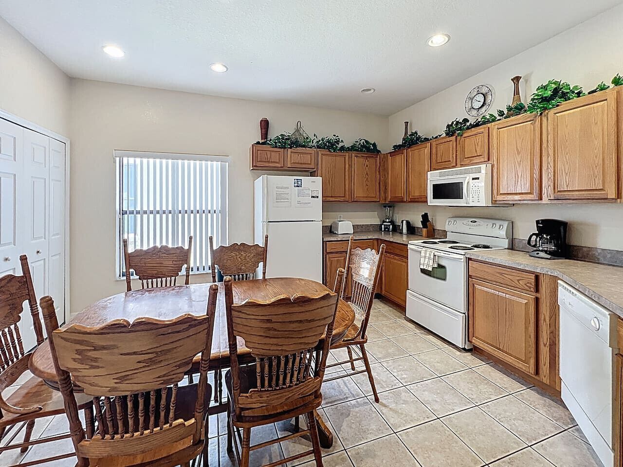 A kitchen with wooden cabinets, a white refrigerator, a stove, and a dining table with chairs.