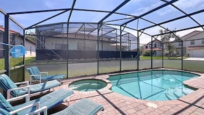 A covered outdoor swimming pool with lounge chairs and a hot tub.