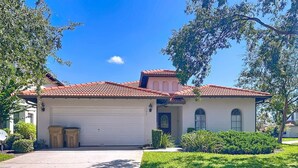 A two-story house with a red-tiled roof, a garage, and a well-maintained lawn.