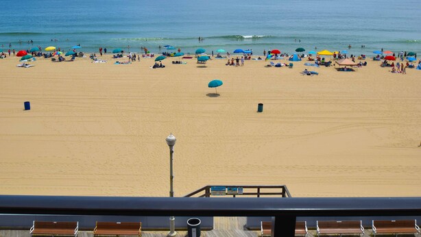 Uma praia com um deck de madeira e bancos com vista para o oceano.
