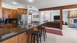 Une cuisine moderne avec des meubles en bois, un réfrigérateur en acier inoxydable et un plan de travail en granit.