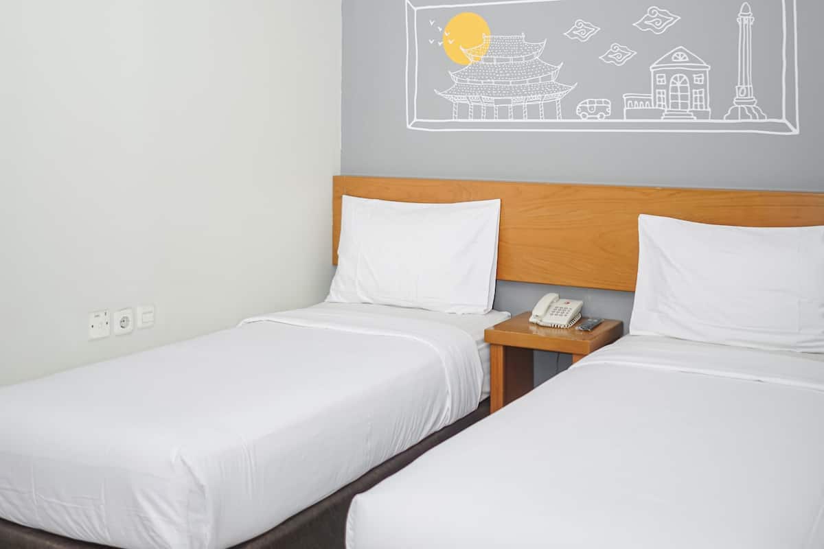 A hotel room with two single beds, a wooden headboard, a bedside table with a phone, and a wall mural depicting a traditional building and a sun.