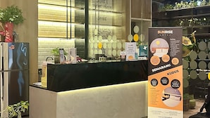 A hotel reception desk with a modern design, a glass partition, and a signboard detailing the hotel's amenities and services. - Sunrise Hotel Semarang (Semarang)
