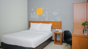 A hotel room with a bed, a desk with a telephone, a chair, and a cabinet. - Sunrise Hotel Semarang (Semarang)