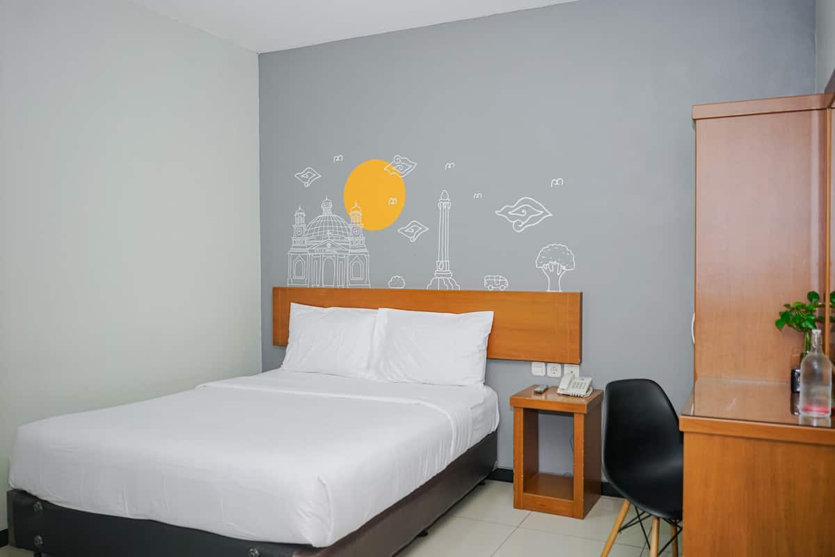 A hotel room with a bed, a desk with a telephone, a chair, and a cabinet.