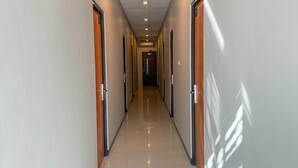A long, narrow hallway with doors on both sides, leading to a central area. - Sunrise Hotel Semarang (Semarang)