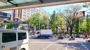 A parking area with a white van and a delivery truck. - Sunrise Hotel Semarang (Semarang)
