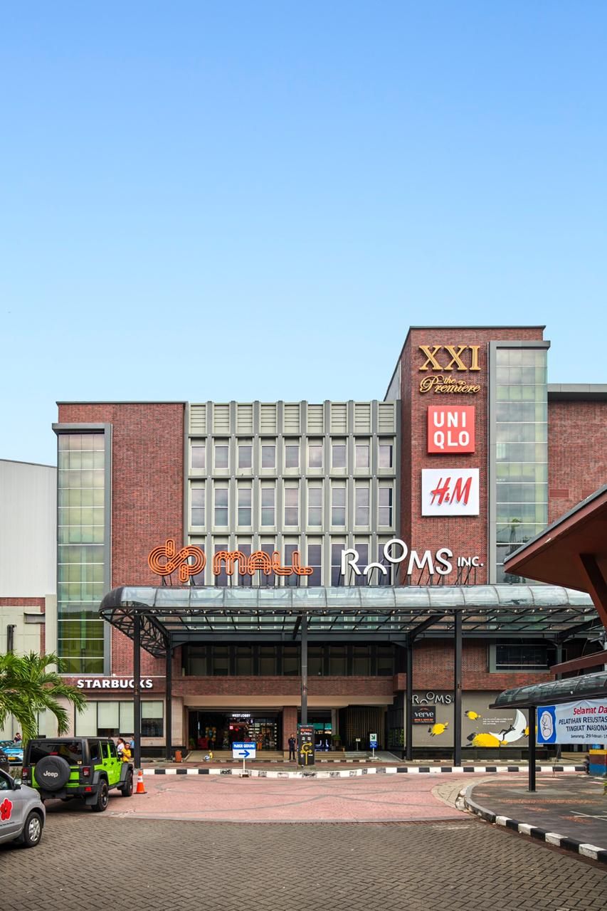 A modern building with a covered entrance, featuring prominent signage for 'XXI The Premiere' and 'ROMS INC.'