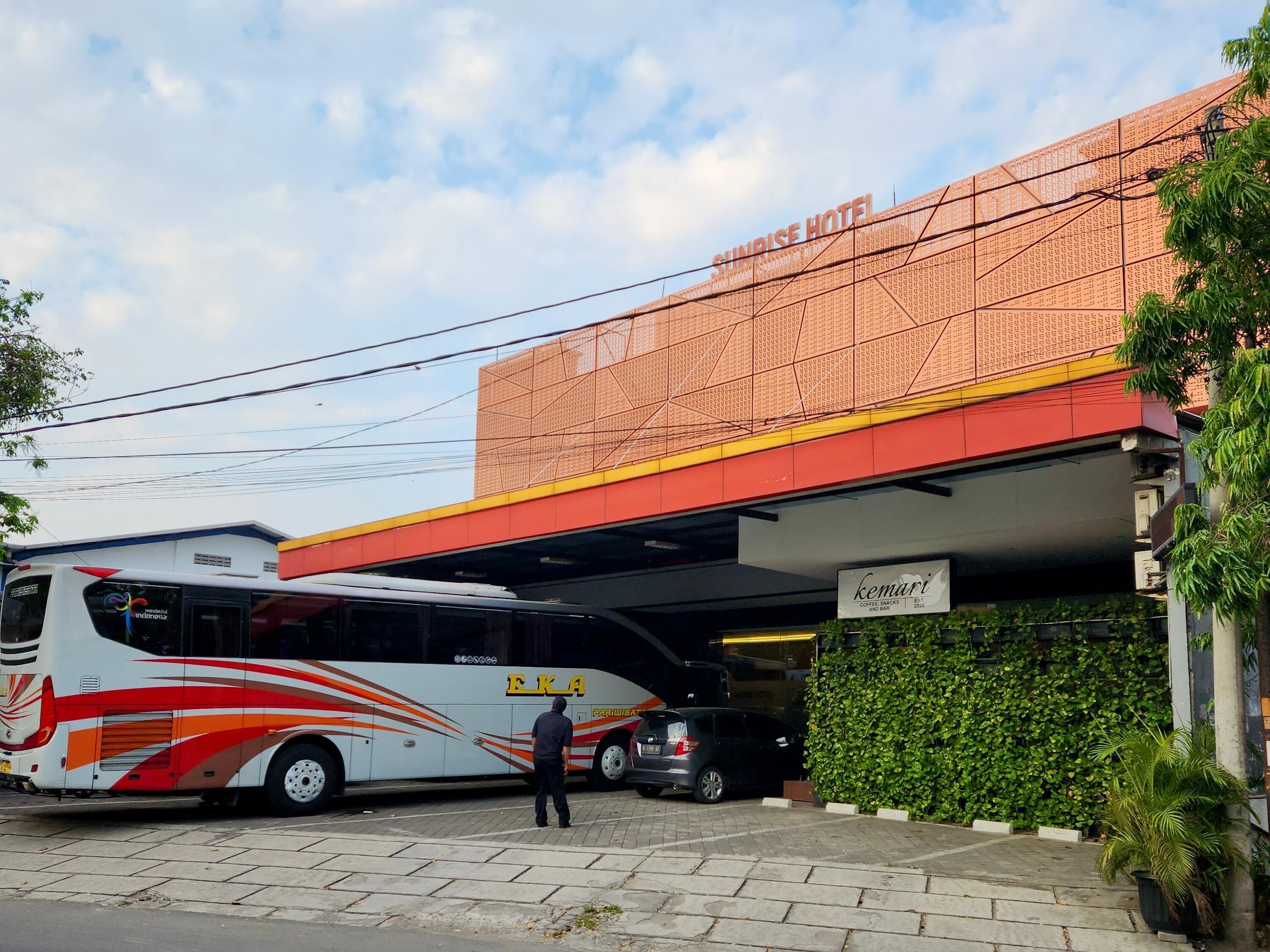 A bus parked in front of a building with a sign reading "Sunrise Hotel".
