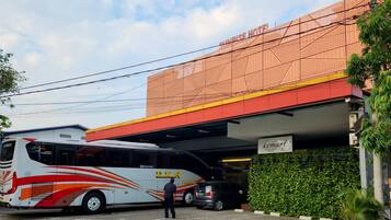 A bus parked in front of a building with a sign reading "Sunrise Hotel".