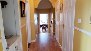 A hallway with wooden flooring, white doors, and yellow walls.