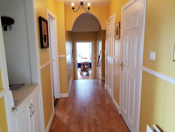 A hallway with wooden flooring, white doors, and yellow walls.