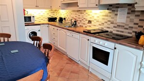 A compact kitchen with white cabinets, a microwave, a toaster, a sink, and a stove.