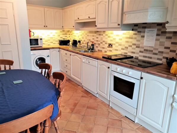 A compact kitchen with white cabinets, a microwave, a toaster, a sink, and a stove. - Bungalow in Kinsale With Great Views just 5 Minutes Walk to Kinsale Centre (Kinsale)