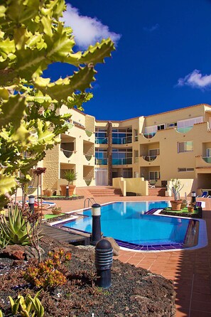 A hotel with a swimming pool surrounded by plants and a clear blue sky. - Apartment, WITH POOL VIEWS - NEXT TO THE BEACH-IDEAL FOR FAMILIES (Costa Calma)