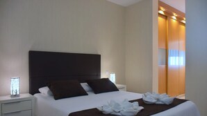 Une chambre d’hôtel moderne avec un grand lit, une table de chevet, une commode et une armoire.