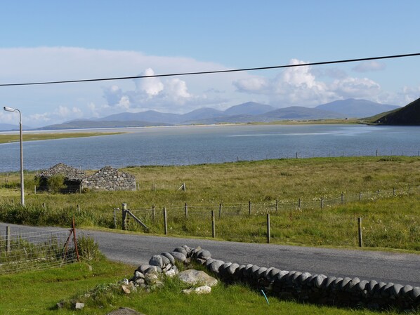 A rural landscape with a road, stone walls, and a body of water.