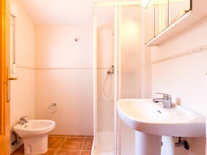 A bathroom with a bidet, a shower, and a sink.