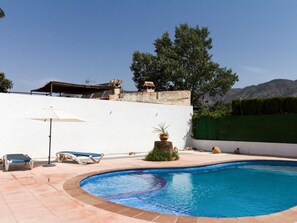 A swimming pool with lounge chairs and a pergola.