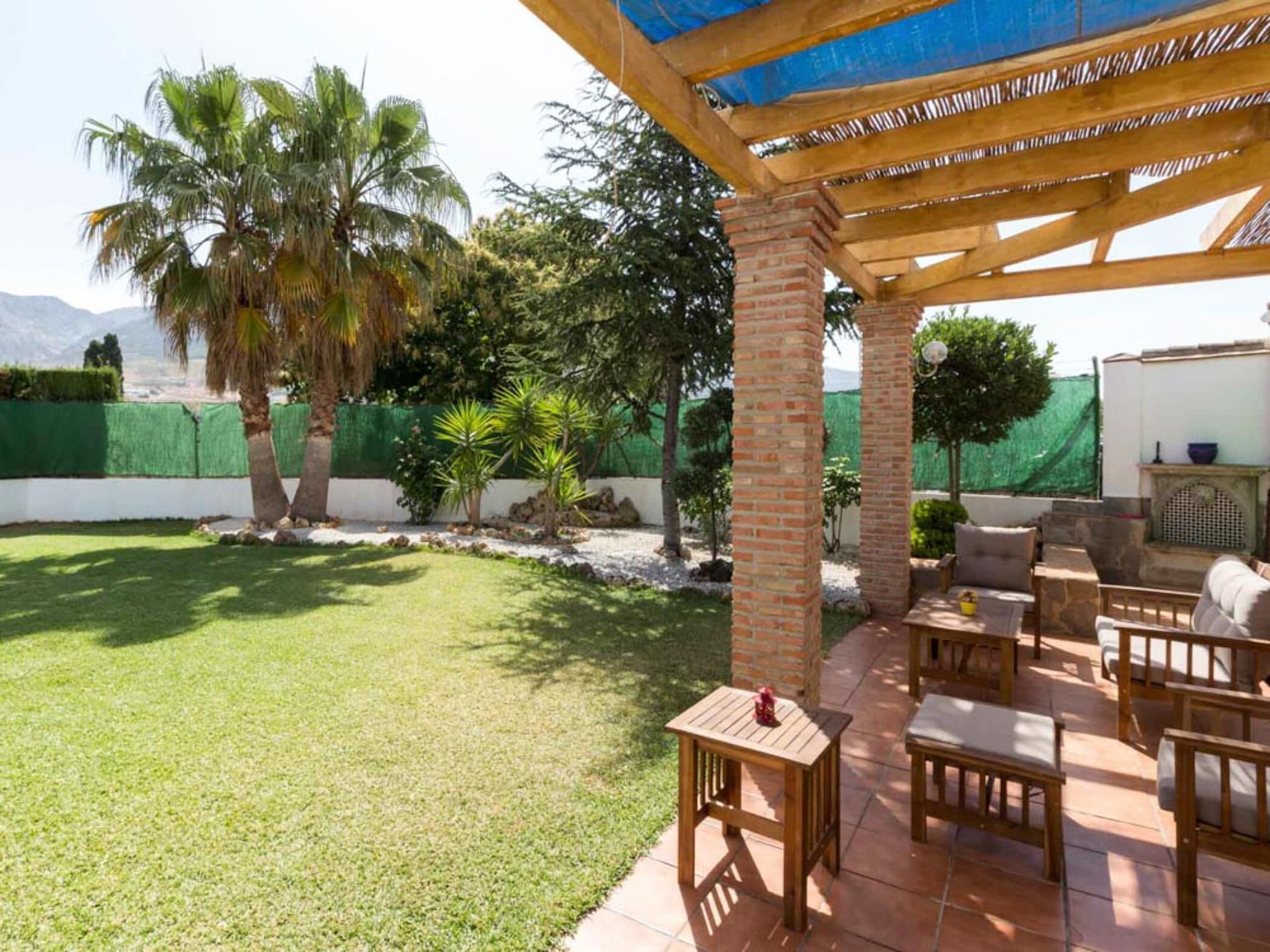 Un espace patio agrémenté d’une pergola, de mobilier d’extérieur et d’une pelouse bien entretenue.