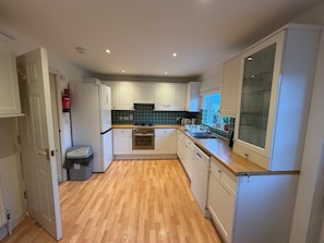 A kitchen with white cabinets, a stainless steel oven, a dishwasher, and a window with a view.