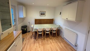 A compact kitchen with a dining table, chairs, and a radiator.