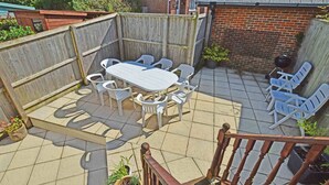 A patio with a wooden table and white plastic chairs, surrounded by a wooden fence. - Mountfield - For families, walkers and cyclists (Freshwater)