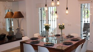 A dining area with a glass table, white chairs, and a vase with white flowers. - Magnificent villa with private pool for 6 people in Moraira - Bénissa (Moraira)